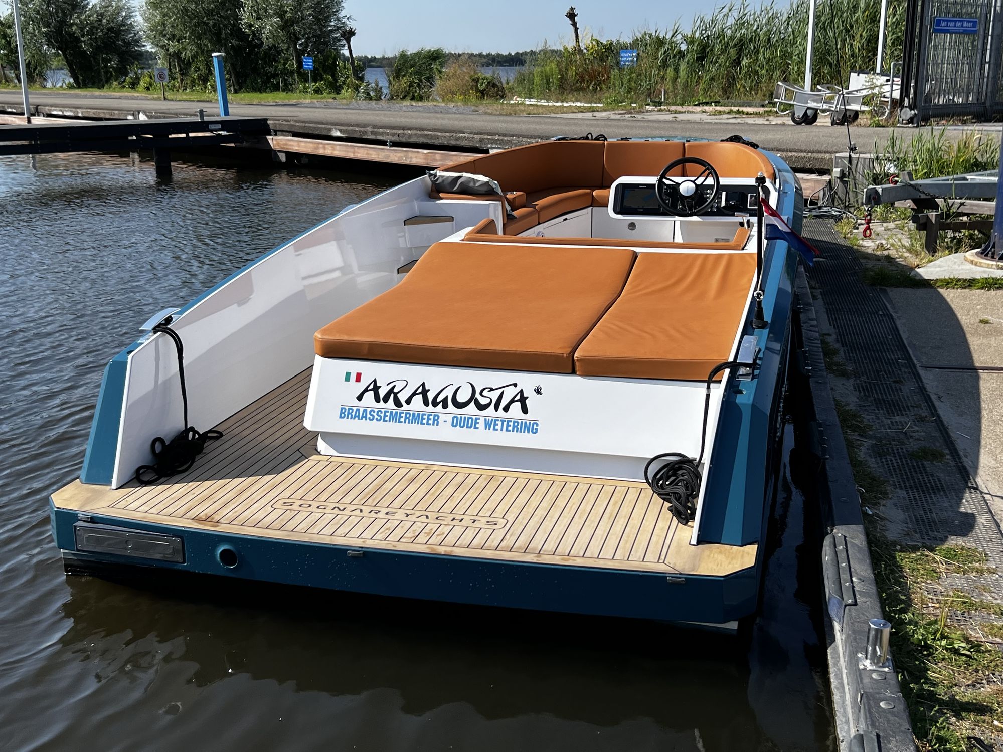 Demonstratieboot Aragosta aan de steiger, met teak zwemplateau en ARAGOSTA-naambord op de spiegel
